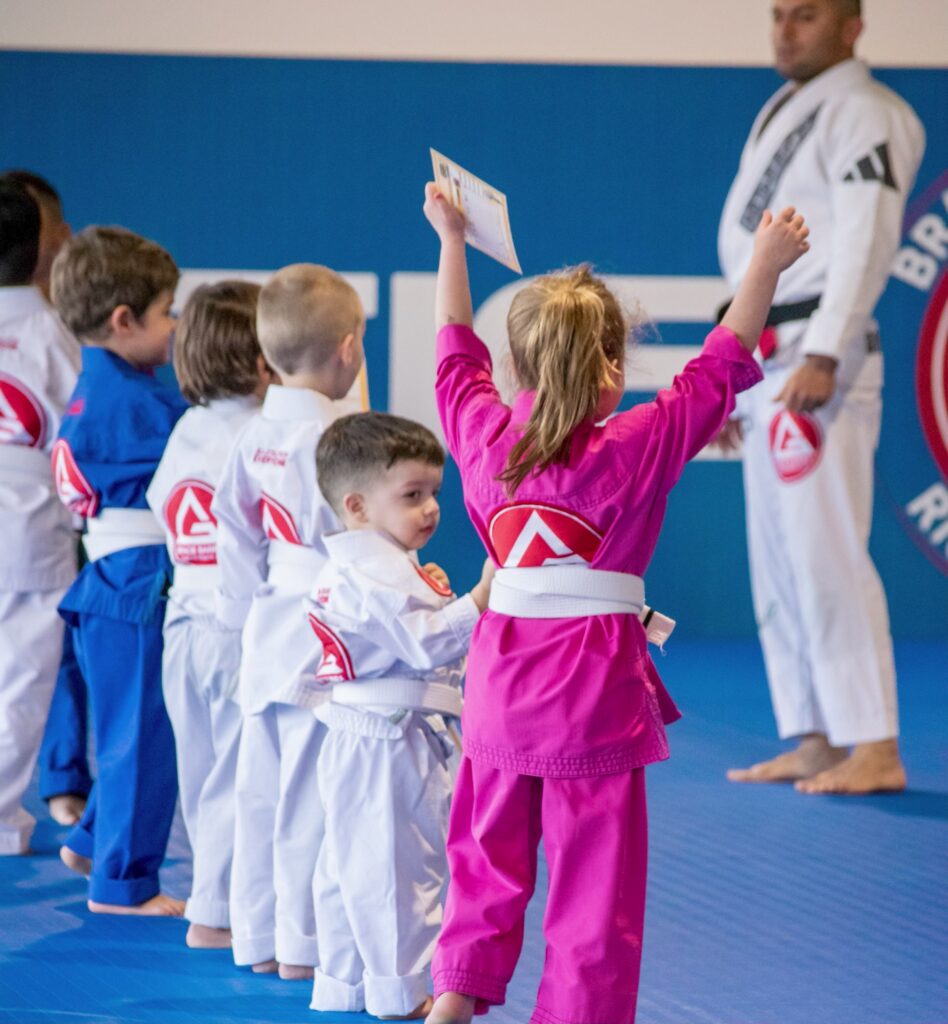 Students in blue gis training Jiu-Jitsu techniques during class.